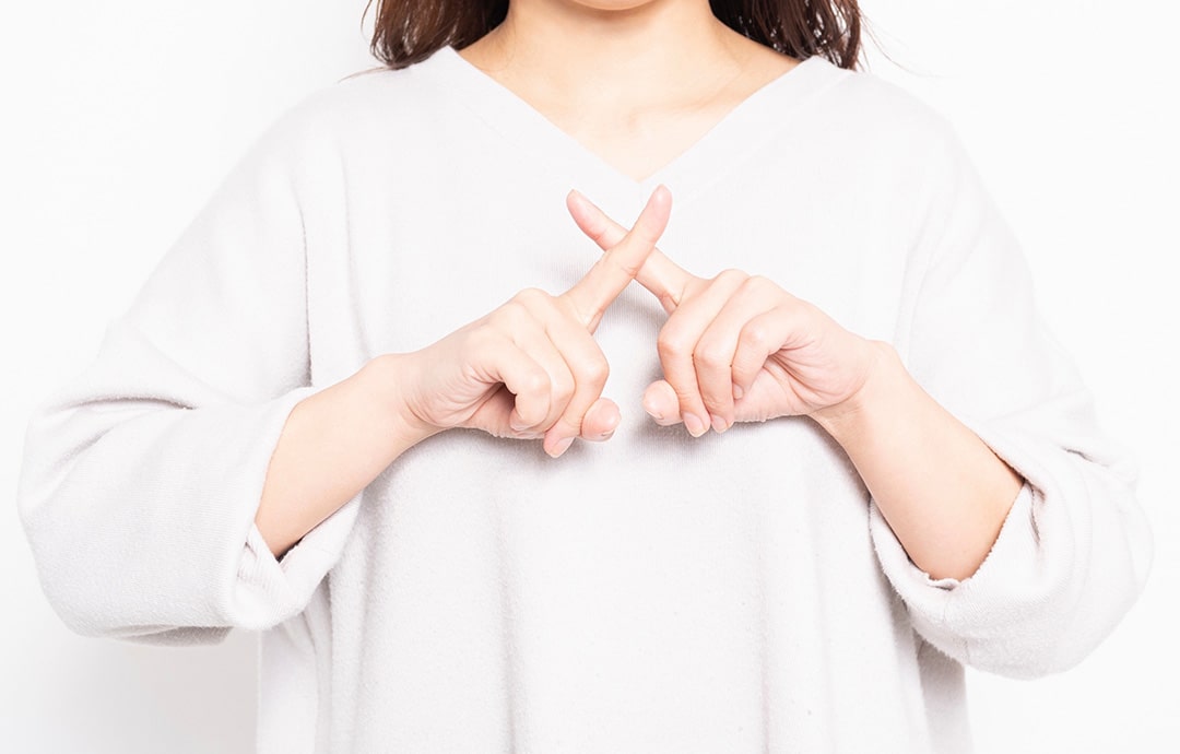 手でバツを作る女性